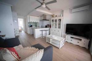 a living room with a couch and a tv and a kitchen at Renovated apartment in La Manga with great sunset in La Manga del Mar Menor