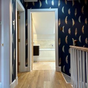 a hallway with a blue wall with a bathroom at The Fiddich Luxury Home in Craigellachie in Craigellachie