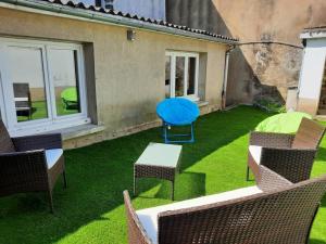 a patio with chairs and a blue table on the grass at Maison centre Connerré - Proche 24h - 11 pers - 4 chambres in Connerré