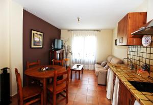 een keuken en een woonkamer met een tafel en een bank bij Apartamentos Pirineos Ordesa in El Pueyo de Araguás