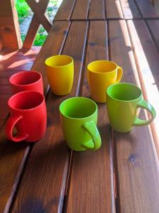 cuatro tazas coloridas sentadas en una mesa de madera en Лісова хатинка en Haivka