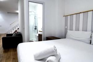 a bedroom with a white bed and a black chair at Comfy apt for 9 in Las Ventas in Madrid
