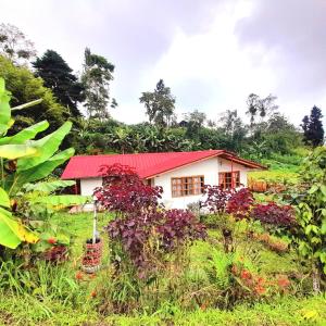 una casa con techo rojo en un campo en LODGE NATAN, en Quito