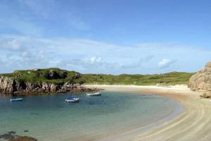 dos barcos sentados en el agua en una playa en Spacious Cottage in Meenaleck near Gweedore County Donegal, en Donegal