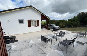 a patio with chairs and a table and a building at Bambou - Gîte du moulin in Petit-Canal