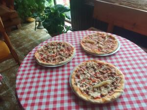 three pizzas on a red and white checkered table at 33 Lipe in Travnik