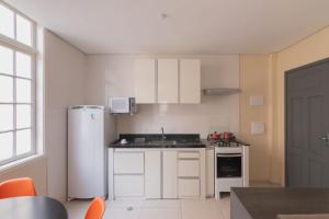 a kitchen with white cabinets and a white refrigerator at Flat - Apartium Palacete Victória in São Paulo