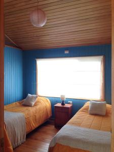 een slaapkamer met 2 bedden en een groot raam bij Casa Barco Chiloe in Quilquico