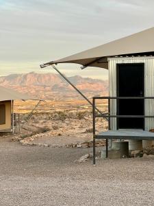 un edificio con toldo y un banco en el desierto en Camp Elena - Luxury Tents Minutes from Big Bend and Restaurants, en Terlingua