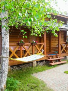 una casa in legno con una panchina e fiori di Лісова хатинка a Haivka