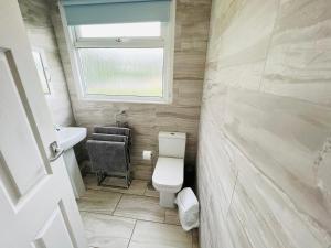 a bathroom with a toilet and a sink and a window at 2 Bedroom Chalet SB22, Sandown Bay, Isle of Wight, Dog Friendly in Sandown