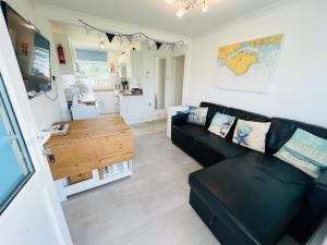a living room with a black couch and a table at 2 Bedroom Chalet SB22, Sandown Bay, Isle of Wight, Dog Friendly in Sandown