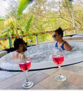 Un uomo e una donna in una vasca idromassaggio con bicchieri da vino di Finca Hotel Spa Zhay a Tibirita