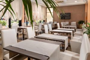 un restaurant avec des tables blanches et des chaises blanches dans l'établissement Hotel Novella, à Misano Adriatico