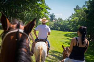 a man and a woman riding horses down a field at Cabana Vinhedos in Bento Gonçalves