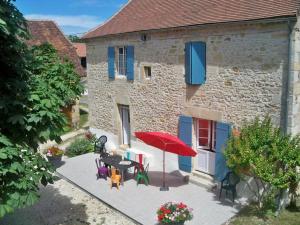 patio con tavolo, sedie e ombrellone rosso di Maison familiale avec piscine privée, jeux pour enfants, salle de sport et Wifi en Dordogne - FR-1-616-70 a Cherveix-Cubas