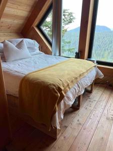 a bed in a room with a large window at Basecamp Strathcona Park View Chalet in Mount Washington