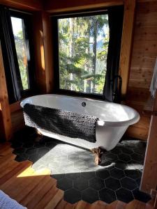 eine große Badewanne in einem Zimmer mit Fenster in der Unterkunft Basecamp Strathcona Park View Chalet in Mount Washington