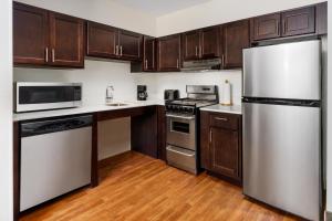 a kitchen with stainless steel appliances and wooden cabinets at TownePlace Suites Manchester-Boston Regional Airport in Manchester