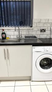 uma cozinha com um lavatório e uma máquina de lavar roupa em Comfortable Modern Bedroom Space with Ensuite near Bramall Lane Stadium and RHH em Sheffield
