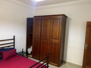 Schlafzimmer mit einem Bett und einem Holzschrank in der Unterkunft Villa sokhna ndeye mbacke in Dakar