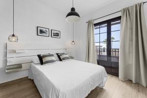 a white bedroom with a bed and a large window at Casahost Casa Ahul Family Time in Costa Teguise