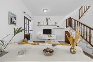 una sala de estar con muebles blancos y una escalera. en Casahost Casa Ahul Family Time, en Costa Teguise