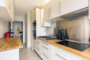 a kitchen with white cabinets and a sink at Appartement climatisé 3 étoiles T3 chic à Strasbourg avec billard et terrasse in Strasbourg +24 photos