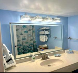 La salle de bains est pourvue d'un lavabo et d'un grand miroir. dans l'établissement Direct Oceanfront With Balcony, à Daytona Beach