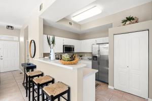 uma cozinha com armários brancos e bancos de bar em Live in Style: Luxury Condo em Henderson