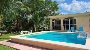 a swimming pool in front of a house at Casita del Arco El Cedral Cozumel in Cozumel