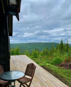 a patio with a table and chairs on a wooden deck at Middagslia - cabin at Skrim with amazing view in Omholt