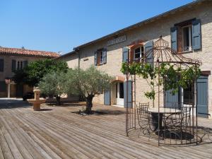einen Innenhof mit einem Gebäude und einer Holzterrasse in der Unterkunft Le Mas de Doat, Gîte de Charme 4 étoiles dans le Triangle d Or proche Gaillac et Albi in Senouillac