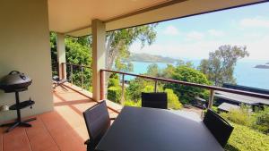 a table and chairs on a balcony with a view of the ocean at Luxury Couples Retreat Hamilton Island and golf buggy - Renovated August 2023 in Hamilton Island