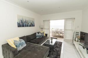 ein Wohnzimmer mit einem Sofa und einem TV in der Unterkunft Dolphins View Luxury Apartment in Port Elizabeth