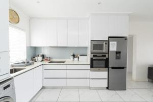 eine Küche mit weißen Schränken und einem Kühlschrank aus Edelstahl in der Unterkunft Dolphins View Luxury Apartment in Port Elizabeth