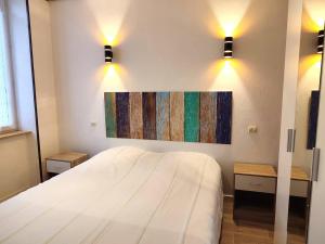 une chambre avec un lit blanc et un tableau au mur dans l'établissement Appartement central à Trébeurden, 500m plage, proche commerces, 2 chambres, 3 salles d'eau - FR-1-368-308, à Trébeurden