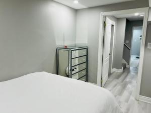 1 dormitorio con cama blanca y vestidor en Cozy 1 BR basement apartment with Free Street Parking & Separate Entrance en Milton