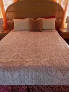 a bed with a orange and white comforter and pillows at Apartment Unforgetable Gardens in Falmouth