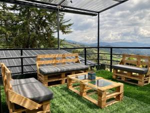 a patio with benches and a table on the grass at ECO CABAÑAS EL ABUELO in La Calera
