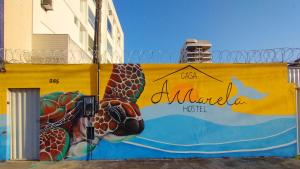 une peinture murale représentant une tortue sur un mur jaune dans l'établissement Casa Amarela Hostel, à Guarapari