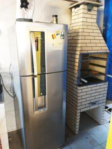 un frigorifero in acciaio inossidabile accanto a un forno in mattoni di Casa Amarela Hostel a Guarapari
