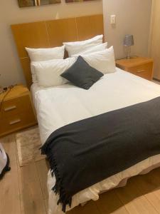 1 cama grande con sábanas y almohadas blancas en Sandton Accomodation Hydro Park, en Johannesburgo