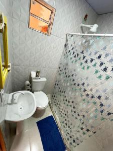 a bathroom with a toilet and a shower curtain at Casa Amarela Hostel in Guarapari