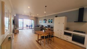 a living room with a table and a kitchen at Luxury Couples Retreat Hamilton Island with Buggy in Hamilton Island