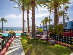 a patio at the beach with palm trees and a table and chairs at Apartamento Primera Línea de Playa in San Bartolomé de Tirajana
