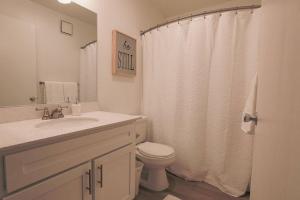 a bathroom with a toilet and a shower curtain at Shabby Chic Oceanside King & 2 Queen bed Pool GYM in Oceanside
