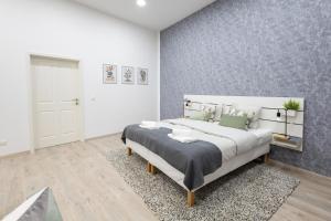 een slaapkamer met een groot bed met een grijze muur bij Family Deluxe a stone throw from the city centre and danube in Wenen