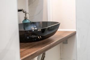 een badkamer met een zwarte wastafel op een houten aanrecht bij Family Deluxe a stone throw from the city centre and danube in Wenen