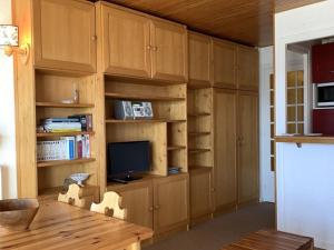 ein Wohnzimmer mit Holzschränken und einem TV in der Unterkunft Appartement Huez, 1 pièce, 4 personnes - FR-1-405-222 in Huez